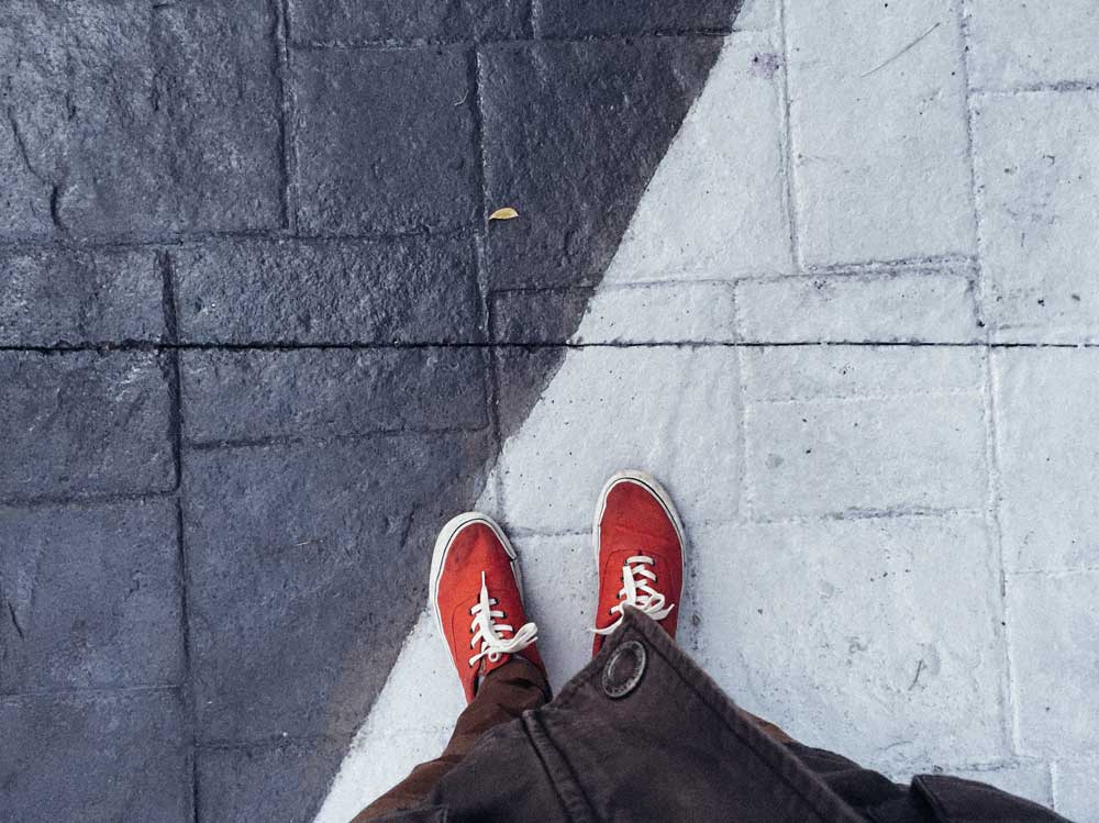 Red gym shoes seen from the point of view of the wearer, on a black and qhite floor split diagonally