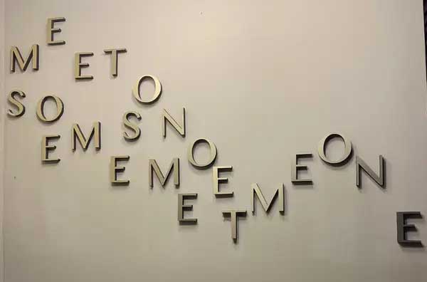 Metal letters on a wall, laid out in such a way that it becomes impossible to discern any meaningful words from them. 
